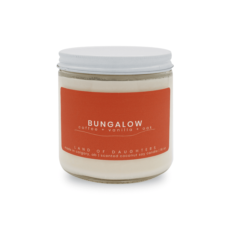 16oz glass jar candle with burnt orange label reading Bungalow, coffee, vanilla, oak on a white background.
