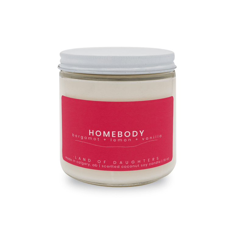 16oz glass jar candle with deep pink label that reads Homebody, lemon + bergamot + vanilla on a white background
