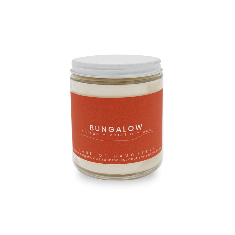 8oz glass jar candle with burnt orange label reading Bungalow, coffee, vanilla, oak on a white background.