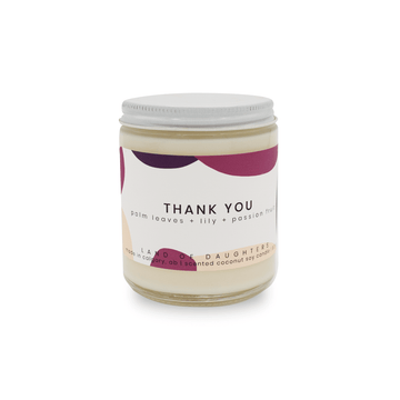8oz Glass Jar candle with white lid and a light green label that reads Thank You, palm leaves +lily + passionfruit is photographed on a white background.