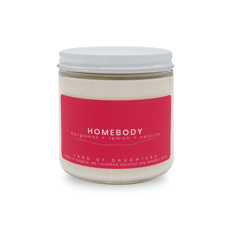 16oz glass jar candle with deep pink label that reads Homebody, lemon + bergamot + vanilla on a white background