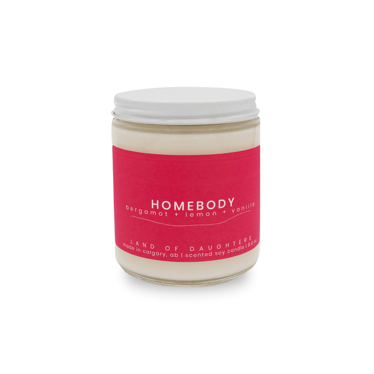 8oz glass jar candle with deep pink label that reads Homebody, lemon + bergamot + vanilla on a white background