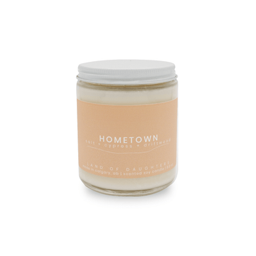 8oz glass jar candle with white lid and a beige label that reads Hometown, salt + cypress + driftwood on a white background